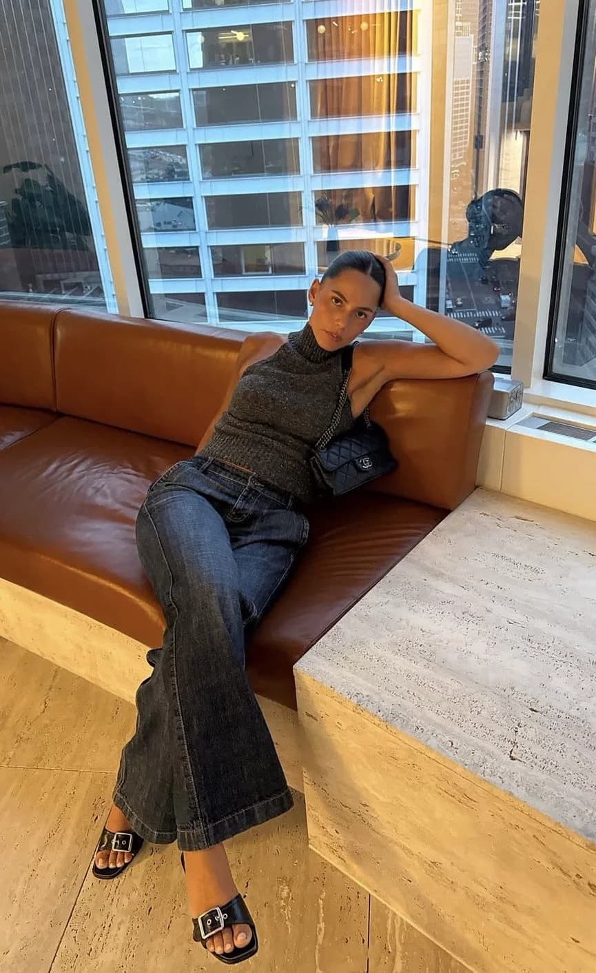 Full-body selfie of a model on a leather couch