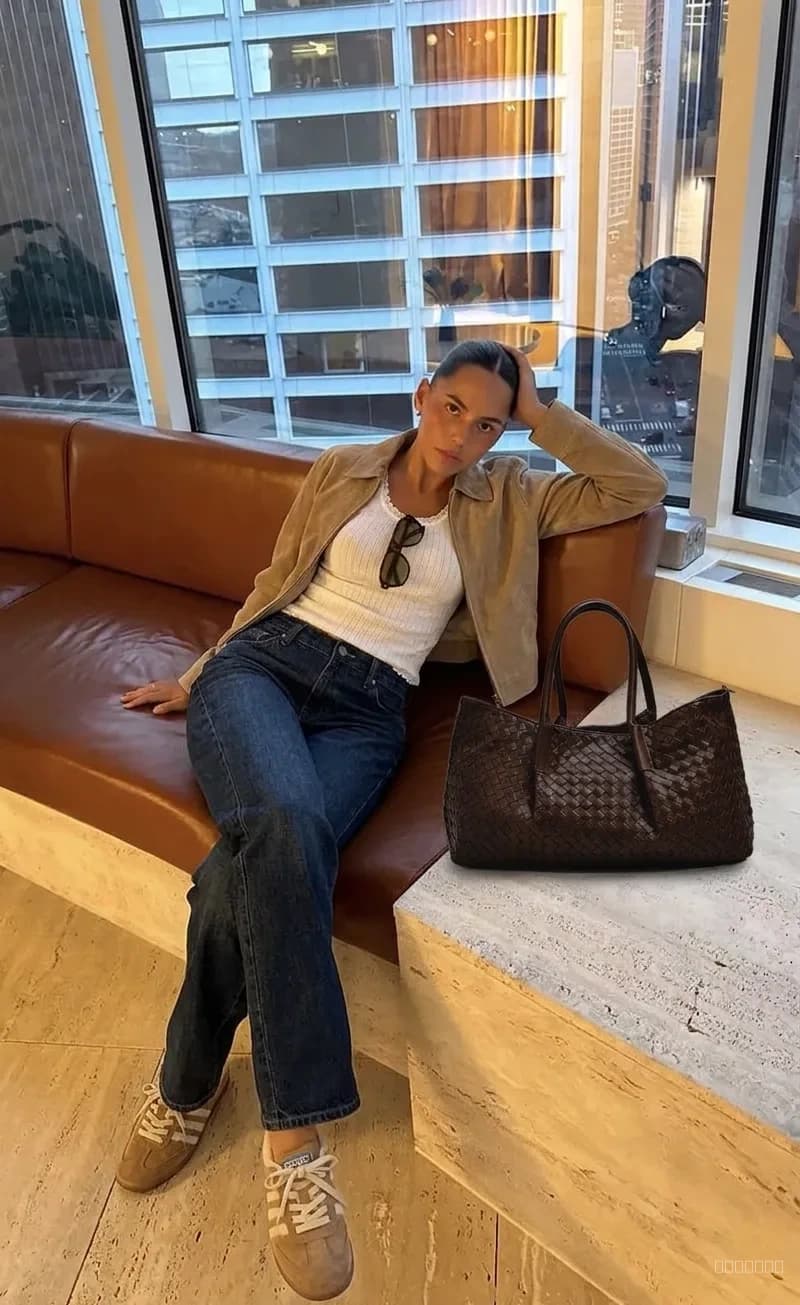 Model wearing the styled outfit: tan suede jacket, white tank, denim jeans, woven tote, suede sneakers
